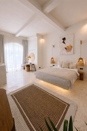 A modern bedroom with a large bed, a round table, and a chair. - New Cozy 1BR Next to the Ocean w Pool+Patio+Garden (Kota Denpasar)