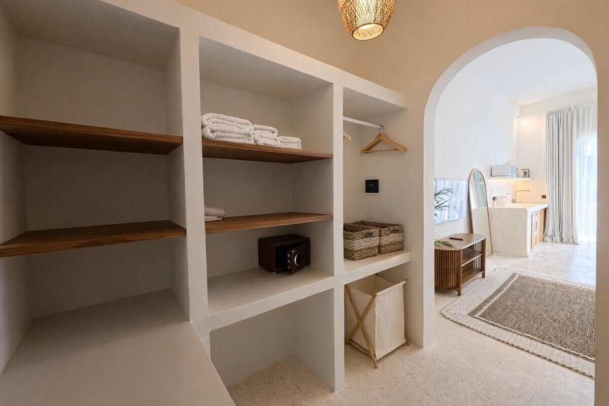 A hotel room with built-in shelving, a walk-in closet, and a view of the bathroom.