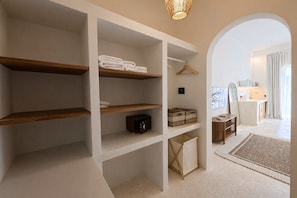 A hotel room with built-in shelving, a walk-in closet, and a view of the bathroom. - New Cozy 1BR Next to the Ocean w Pool+Patio+Garden (Kota Denpasar)