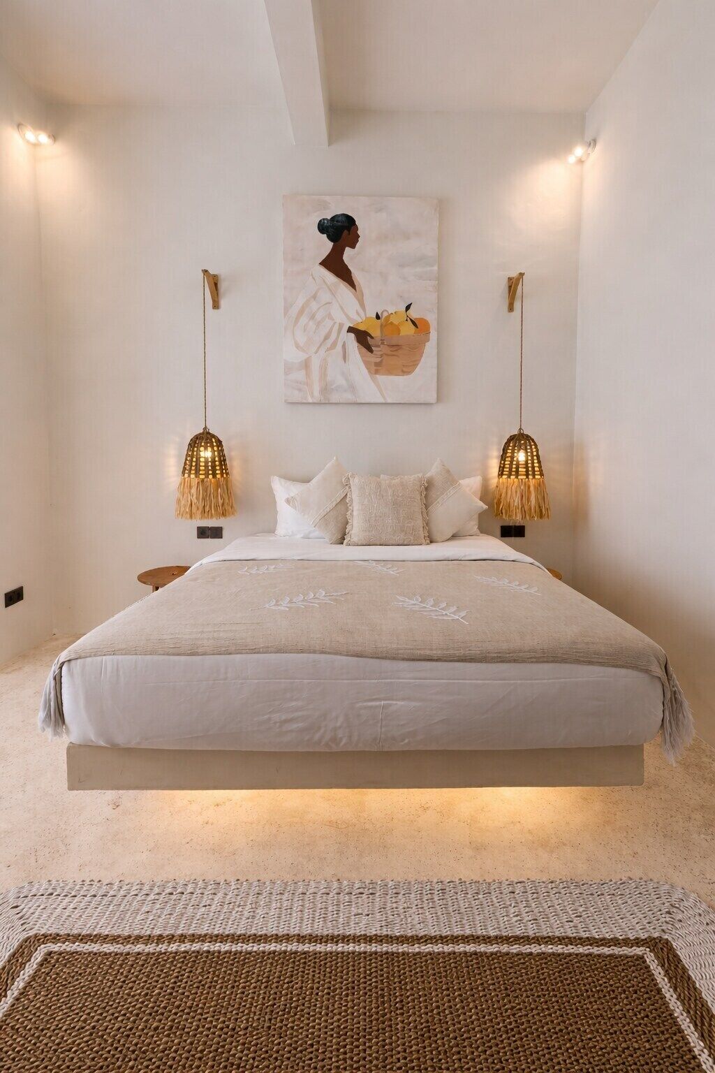Un dormitorio con una cama, dos lámparas de pared, un cuadro y una alfombra con textura.