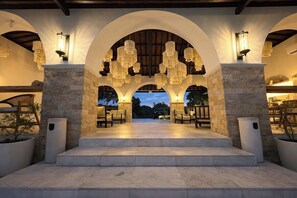 An outdoor covered area with stone pillars, a set of steps leading to a seating area, and hanging light fixtures. - Sanur's Best 1BR Next to the Ocean w Pool&Garden (Kecamatan Denpasar Selatan)