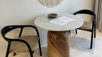 A round table with a wooden base, two black chairs, and a wall-mounted decorative piece.