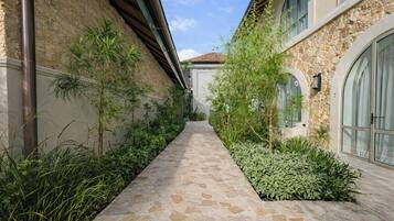 Un sentiero in pietra costeggiato da vegetazione lussureggiante e un edificio in pietra con finestre ad arco.