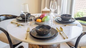 Una mesa de comedor con cuencos negros, vasos transparentes y cubiertos dorados.