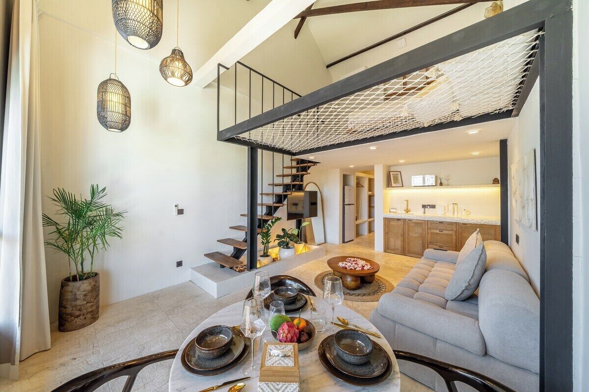 Una sala moderna con comedor, una escalera y una cocina al fondo.