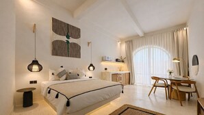 Un dormitorio moderno con cama, mesitas de noche, un escritorio y una zona de comedor.
