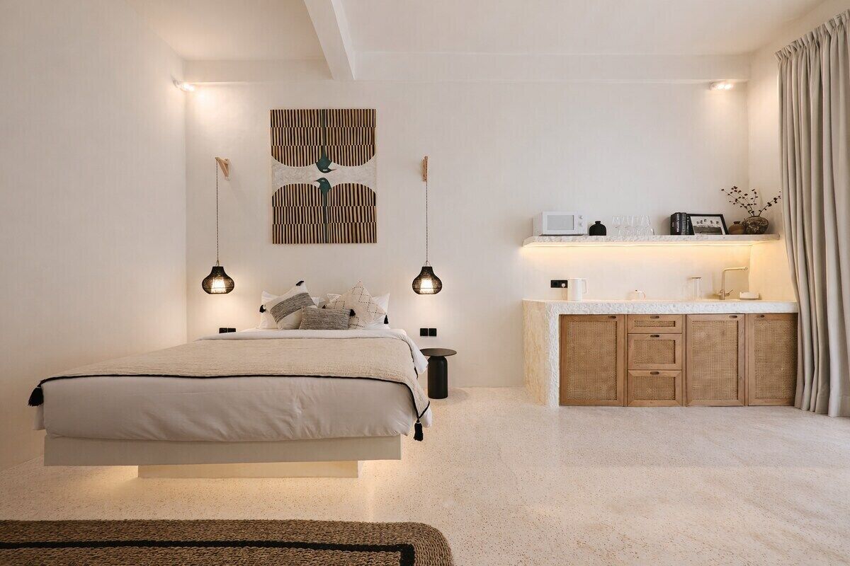Een slaapkamer met een bed, nachtkastjes, een dressoir en een wandlamp.