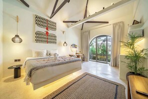 Quarto moderno com uma cama grande, vista para o exterior e uma peça de arte geométrica única na parede.