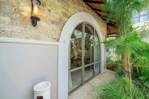 A stone building with a glass door entrance, a trash can, and a small tree. - New Apartments in Sanur+5 min to Ocean+Pool (Kota Denpasar)