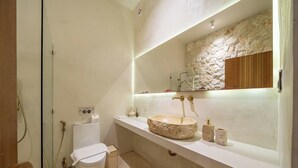 Un baño moderno con un lavabo de piedra, inodoro y zona de ducha.