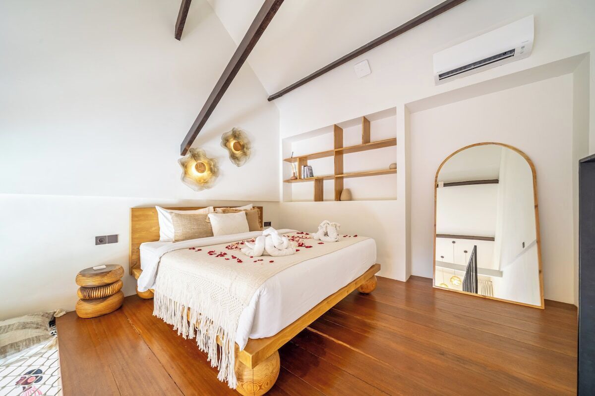A modern bedroom with a wooden bed, white bedding, and a large mirror.