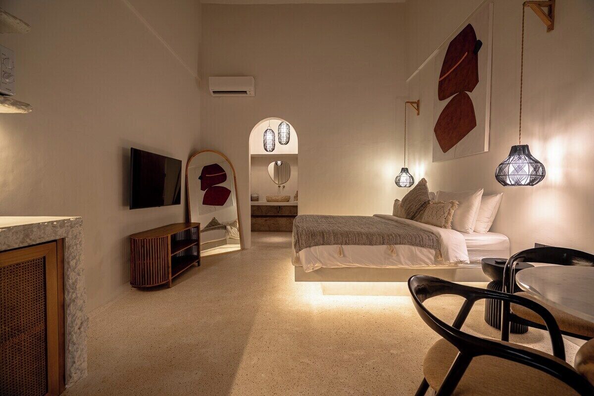 Een slaapkamer met een bed, nachtkastje en een aan de muur bevestigde televisie.