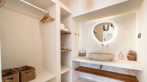 Ein Badezimmer mit einem weißen Waschbecken, einem Spiegel und Regalen mit Handtüchern und Körben.