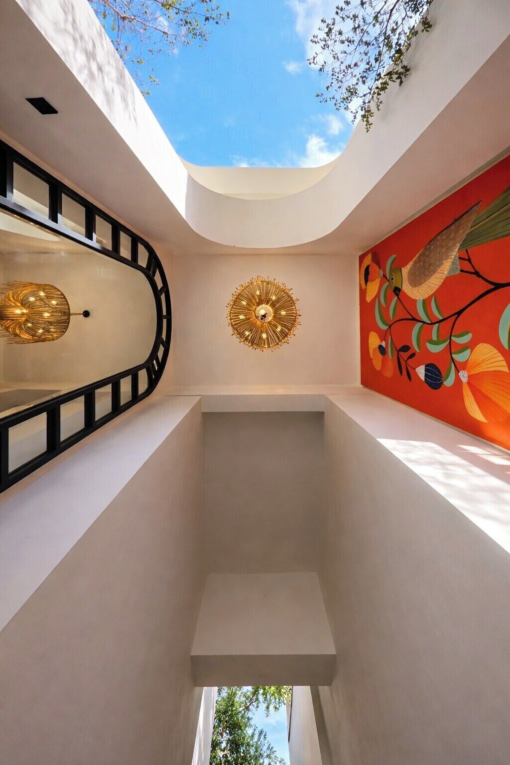 Een modern interieur met dakraam, decoratieve wandversiering en een bijzondere plafondlamp.