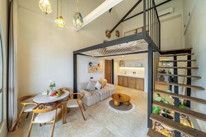 A modern interior with a dining area, sofa, and staircase. - Boho Two-Storey Flat Next to Sanur Beach w Bathtub (Kota Denpasar)