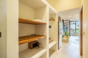 Un couloir doté d’étagères en bois intégrées, d’un meuble à chaussures et offrant une vue sur un escalier menant à un balcon agrémenté de plantes.