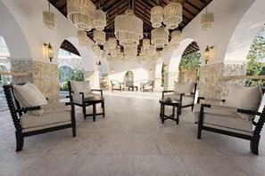 A spacious outdoor lounge area with multiple seating arrangements, including sofas and chairs, under a series of hanging chandeliers. - Boho Two-Storey Flat Next to Sanur Beach w Bathtub (Kota Denpasar)