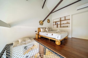 Une chambre avec un lit en bois, une petite table de chevet, une étagère murale agrémentée d’objets décoratifs et un plafond en pente avec des poutres en bois.