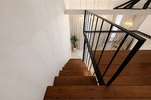 Un escalier en bois avec des rampes noires menant à un palier.