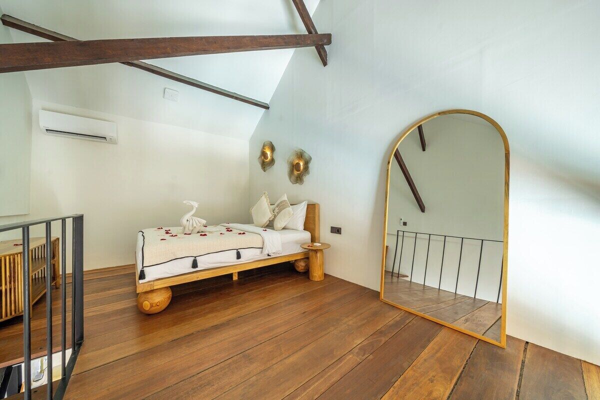 Una camera da letto con un letto di legno, un comodino, uno specchio e una scala.
