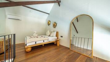 Una camera da letto con un letto di legno, un comodino, uno specchio e una scala.