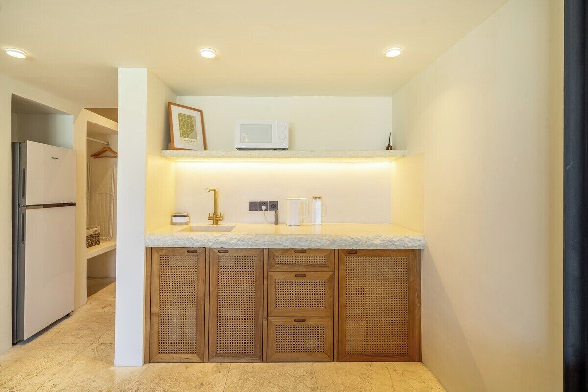 A compact kitchen with a built-in refrigerator, a microwave, and a sink with a gold faucet.