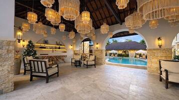 An indoor pool area with stone walls, hanging macrame chandeliers, and seating arrangements.