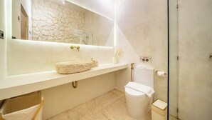 Un bany modern amb una paret de pedra, un lavabo gran i un vàter.