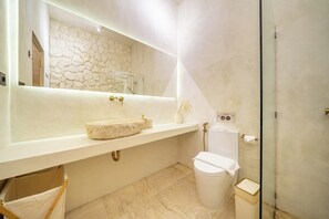 Ein modernes Badezimmer mit einer Steinwand, einem großen Waschbecken und einer Toilette.