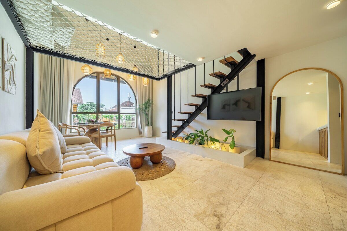 Una sala moderna con un sofá, una mesa de centro y una escalera que lleva a un balcón.