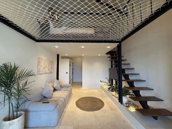 A modern interior with a sofa, a staircase, and a plant.