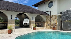 A poolside area with a clear pool, stone walls, and outdoor seating.
