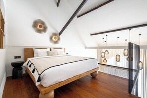 A modern bedroom with a wooden bed, a round wall light, and a hanging light fixture.