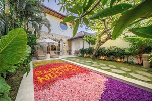 A courtyard with a stone wall, a circular window, and a seating area with cushions. - Chic 2BR Villa by Sanur Beach w Pool +Room Jacuzzi (Kota Denpasar)
