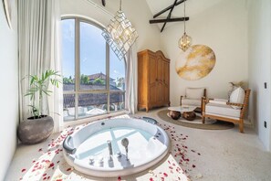 A spa room with a large bathtub, wooden furniture, and a view through a large window. - Chic 2BR Villa by Sanur Beach w Pool +Room Jacuzzi (Kota Denpasar)