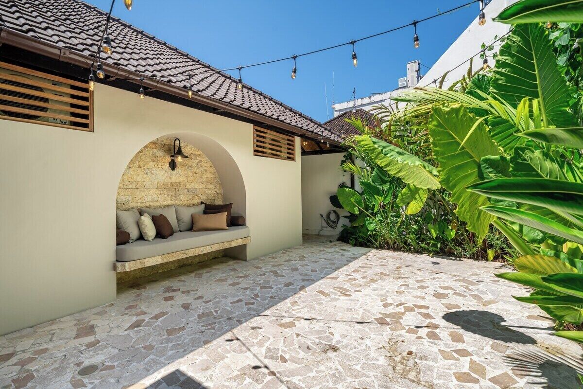An outdoor seating area with a stone floor, a stone wall, and a plant.