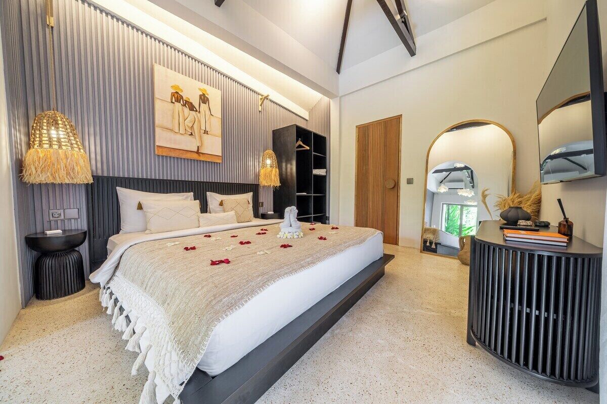 A modern bedroom with a large bed, bedside tables, a wardrobe, and a mirror.