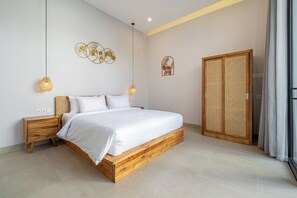 A bedroom with a wooden bed, bedside tables, a wall-mounted light fixture, and a woven door. - Cozy 2BR in Sanur w Pool, Rooftop & Beach Access (Kota Denpasar)