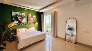 A modern bedroom with a large bed, green accent walls, artwork, and a large mirror. - Chic 3BR in Nusa Dua w Ocean View+Cinema+Rooftop (Kabupaten Badung)