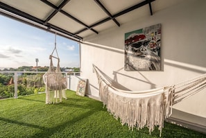 A hammock on a balcony with a view of the city. - Chic 3BR in Nusa Dua w Ocean View+Cinema+Rooftop (Kabupaten Badung)