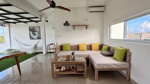 A modern living room with a sofa set, a glass coffee table, and a hammock. - Chic 3BR in Nusa Dua w Ocean View+Cinema+Rooftop (Kabupaten Badung)