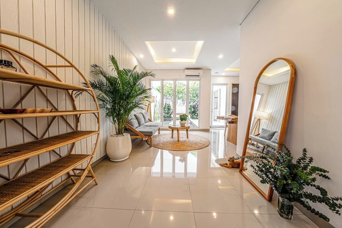 A modern interior with a central seating area, a large mirror, and a bamboo shelf unit.