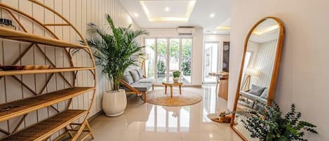A modern interior with a central seating area, a large mirror, and a bamboo shelf unit.