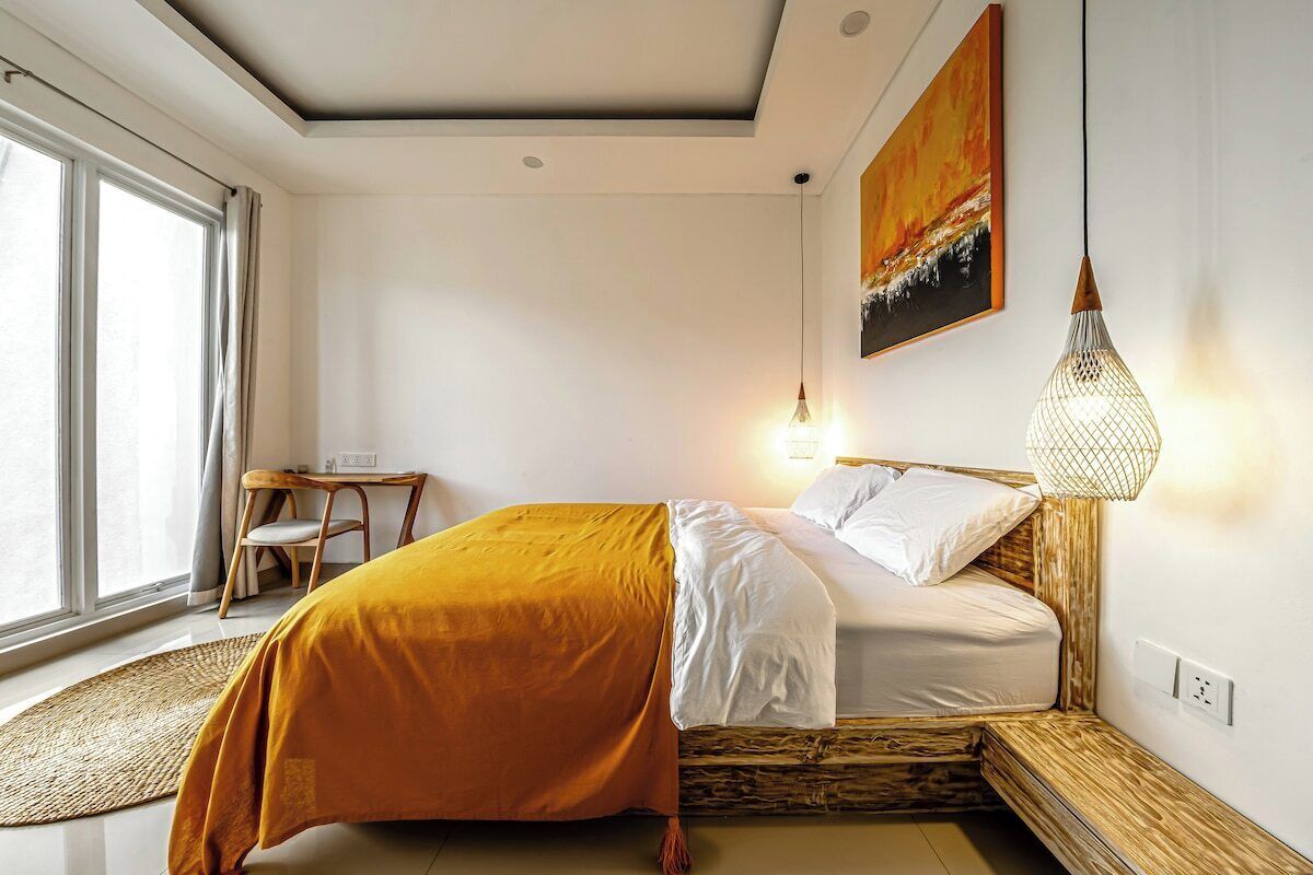 A bedroom with a bed, a desk, and a window.