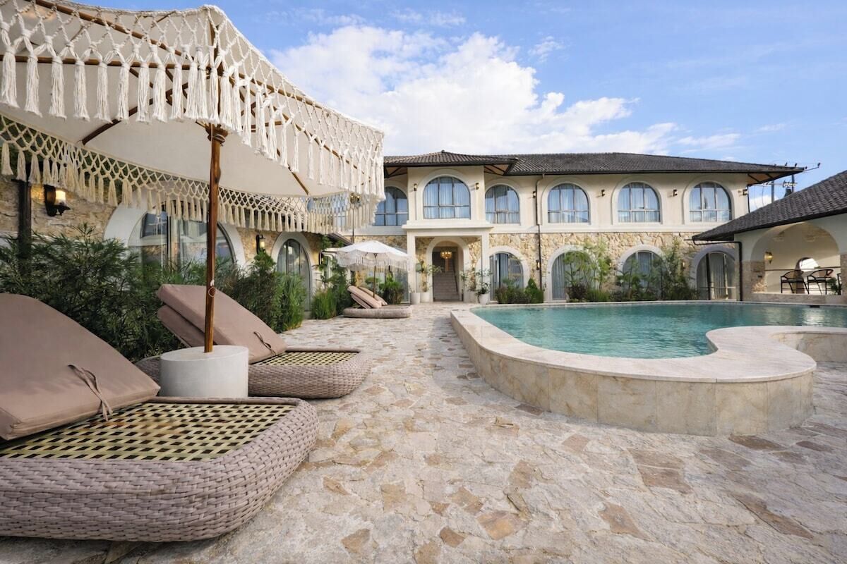 A pool area with lounge chairs and a stone floor.