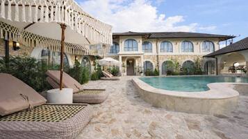 A pool area with lounge chairs and a stone floor.