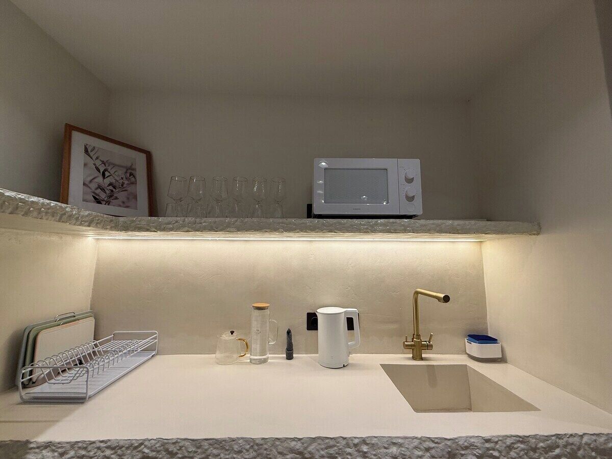 A compact kitchen with a microwave, sink, and various kitchen items.