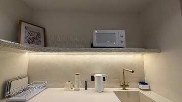 A compact kitchen with a microwave, sink, and various kitchen items.