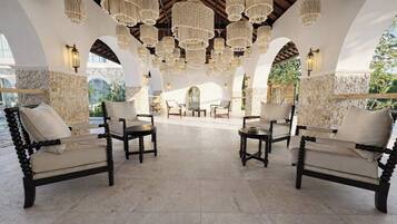 Amplia zona de estar al aire libre con diversas opciones de asientos, incluyendo sofás y sillones, bajo una serie de candelabros colgantes.