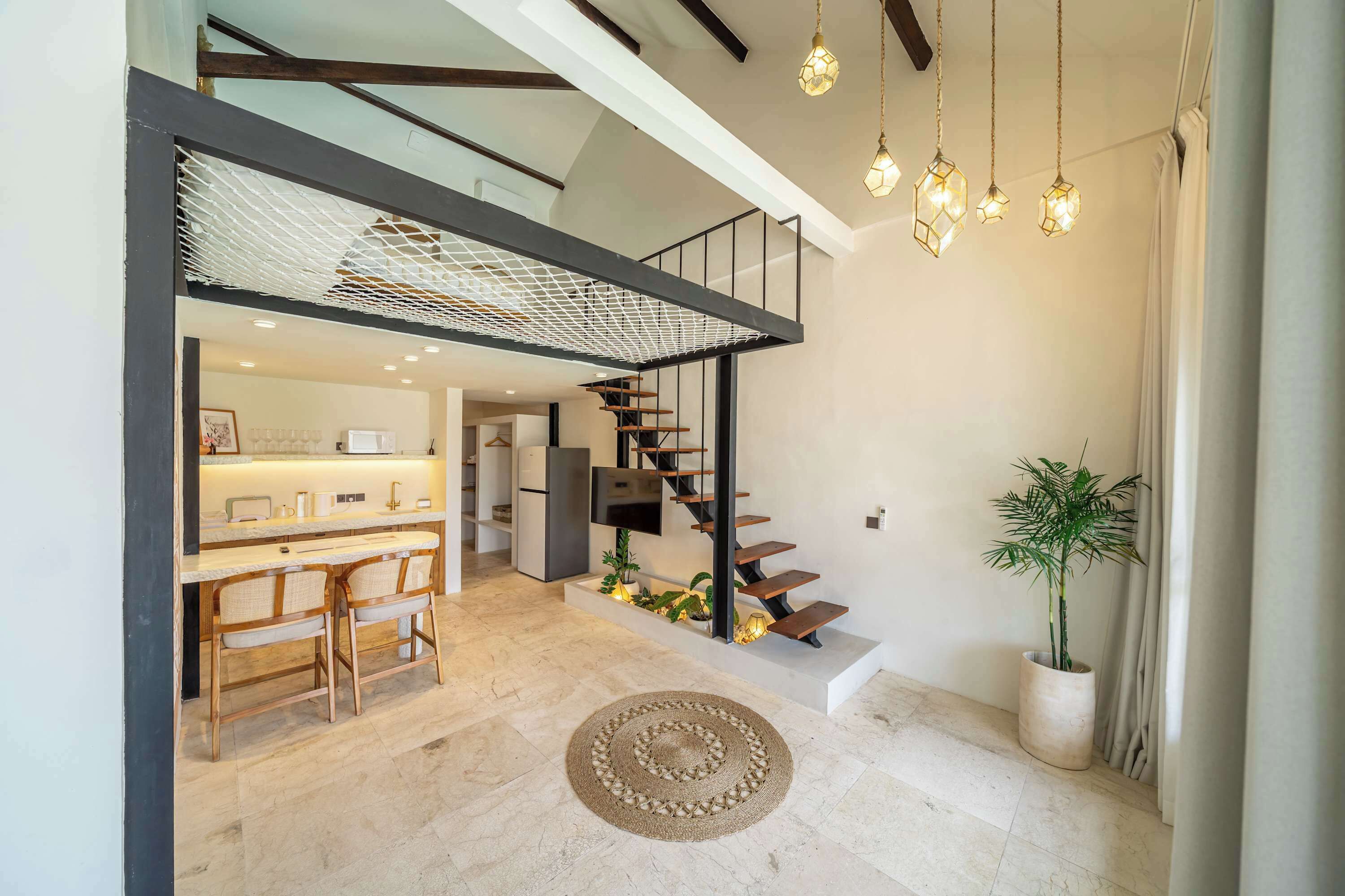 A modern interior with a kitchen, dining area, and a staircase leading to an upper level.
